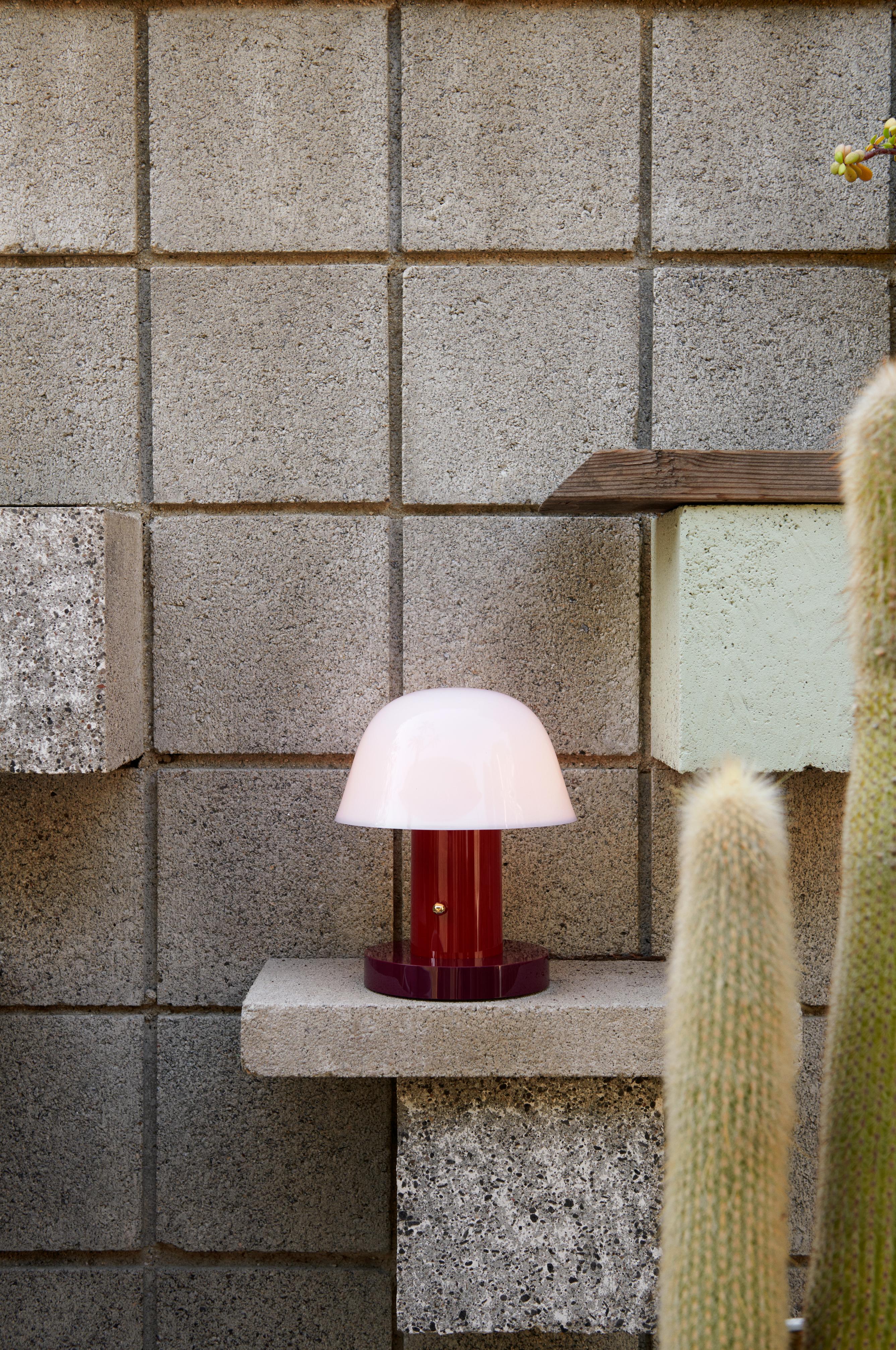 Tragbare Lampe SETAGO JH27 mit cremefarbenem Schirm und dunkelrotem Fuß.