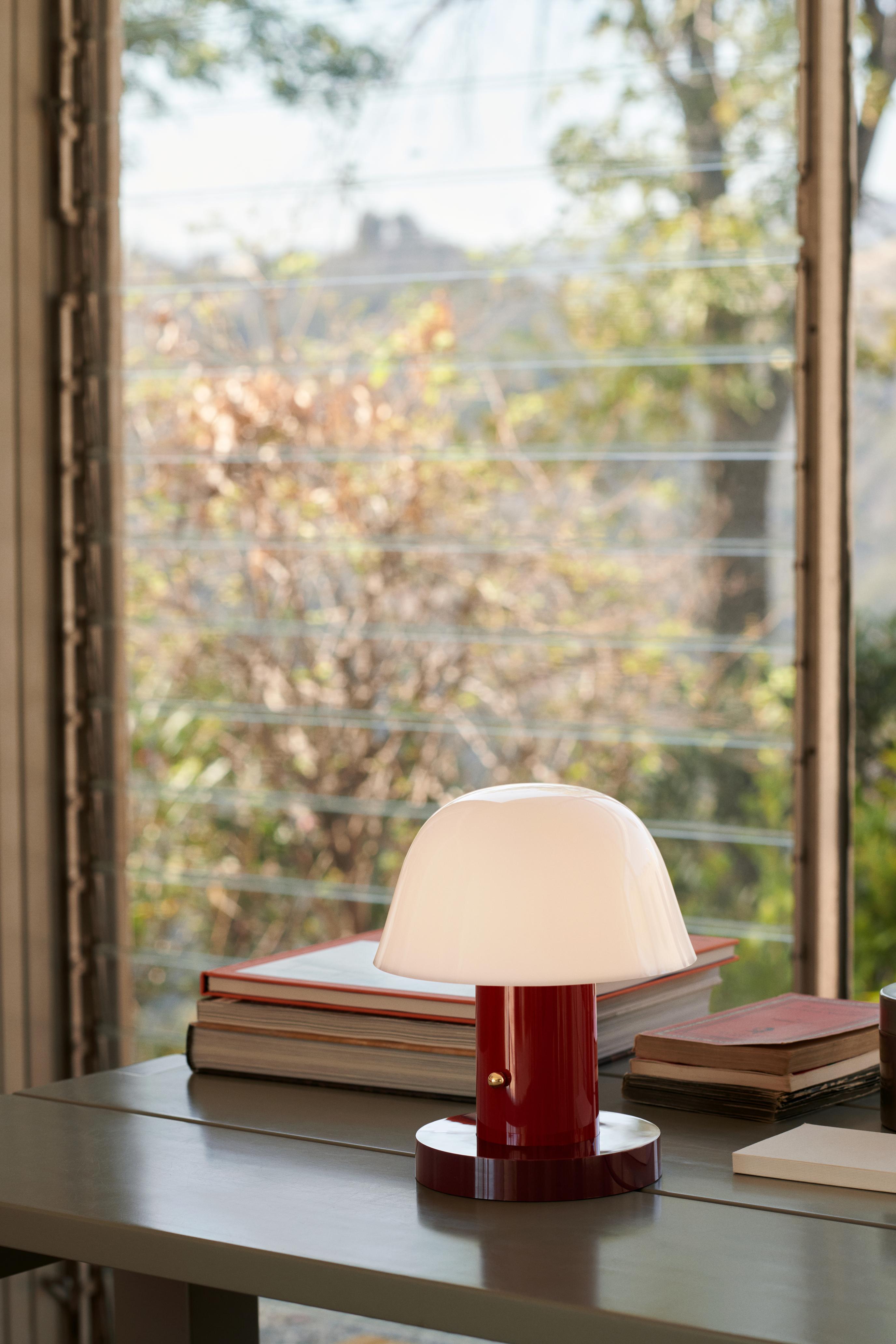 Tragbare Lampe SETAGO JH27 mit cremefarbenem Schirm und dunkelrotem Fuß.