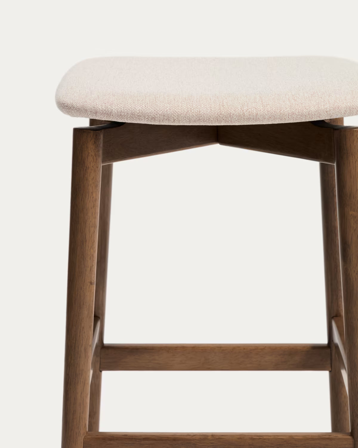 Hocker EVERA in beigem Chenille mit dunklem furniertem Eichenfuß.